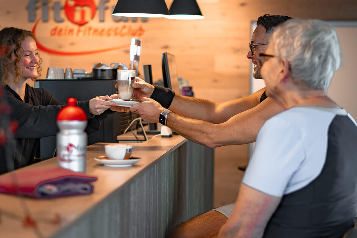 Zwei Mitglieder an der Theke lächelnd beim Kaffee trinken im Fit 'n Fun Gau-Algesheim bei Ingelheim